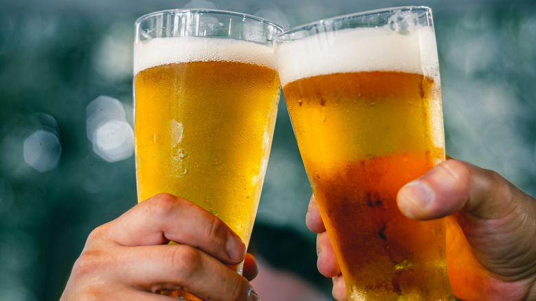 Close-up,View,Of,A,Two,Glass,Of,Beer,In,Hand.